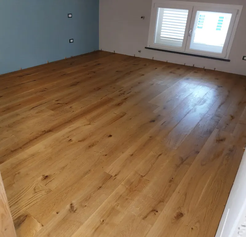 Camera con parquet prefinito in rovere nodato e parete azzurra