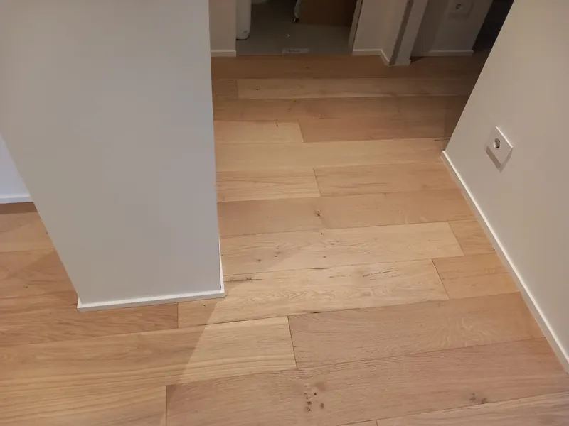 Ingresso con parquet prefinito in rovere chiaro e battiscopa bianco