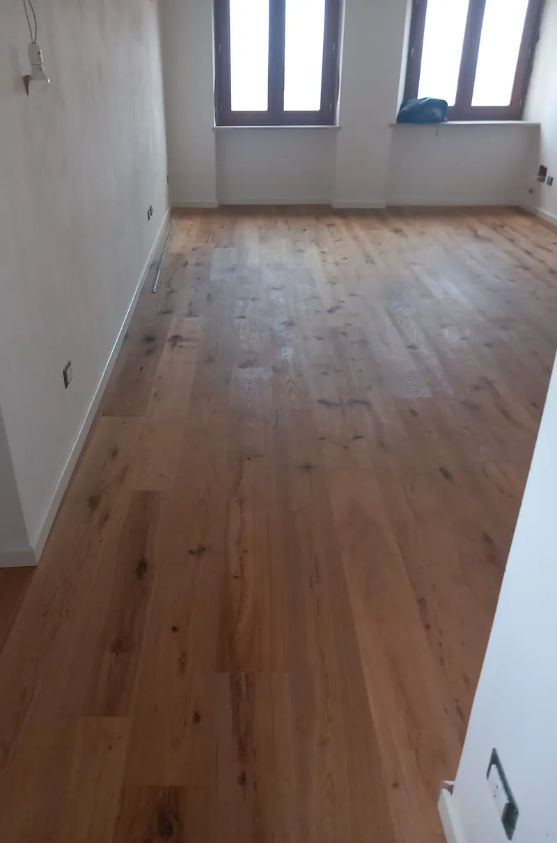 Stanza lunga con parquet prefinito in rovere rustico e due finestre