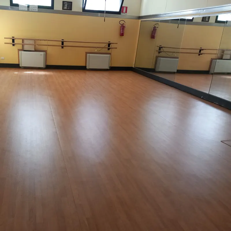 Sala danza con pavimento effetto legno, sbarre e specchi